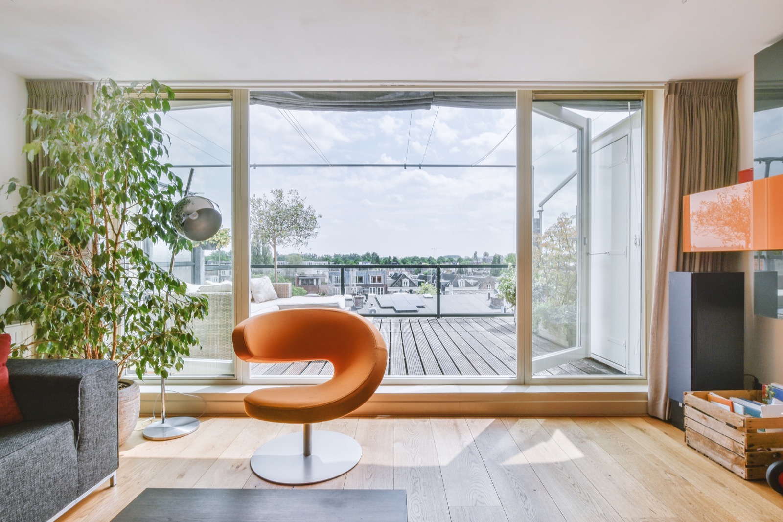 Helles Wohnzimmer einer Wohnung mit großer Glastür zur Terrasse und Blick über die Dächer der Stadt
